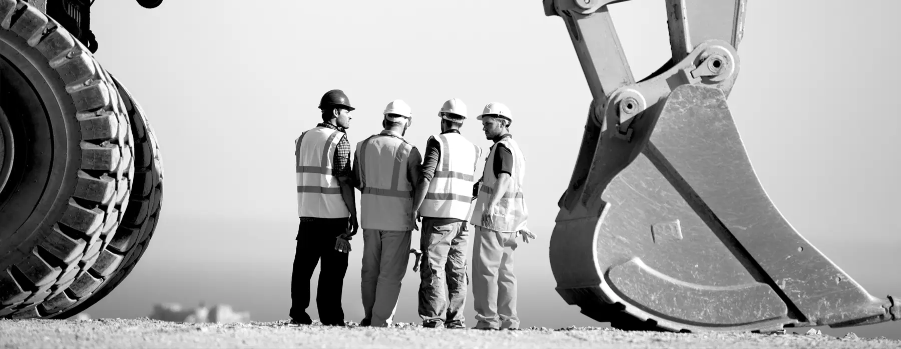 Four construction workers talking near heavy equipment