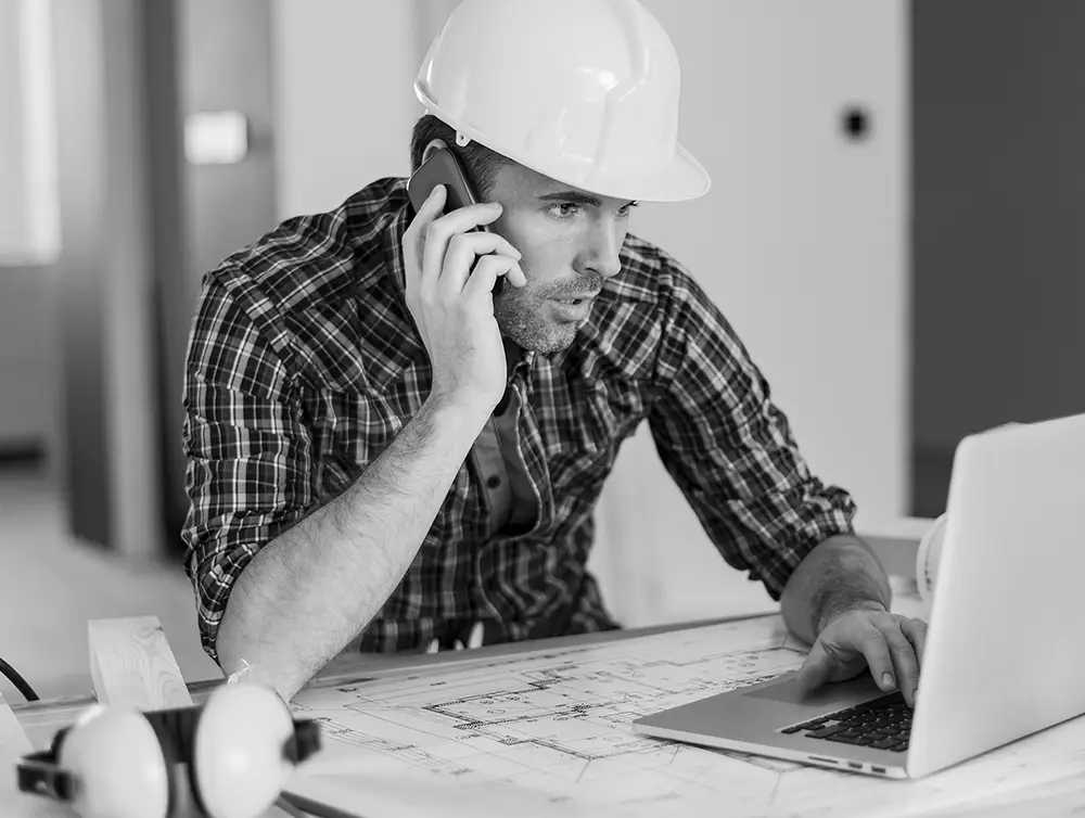 Construction worker at computer and on the phone