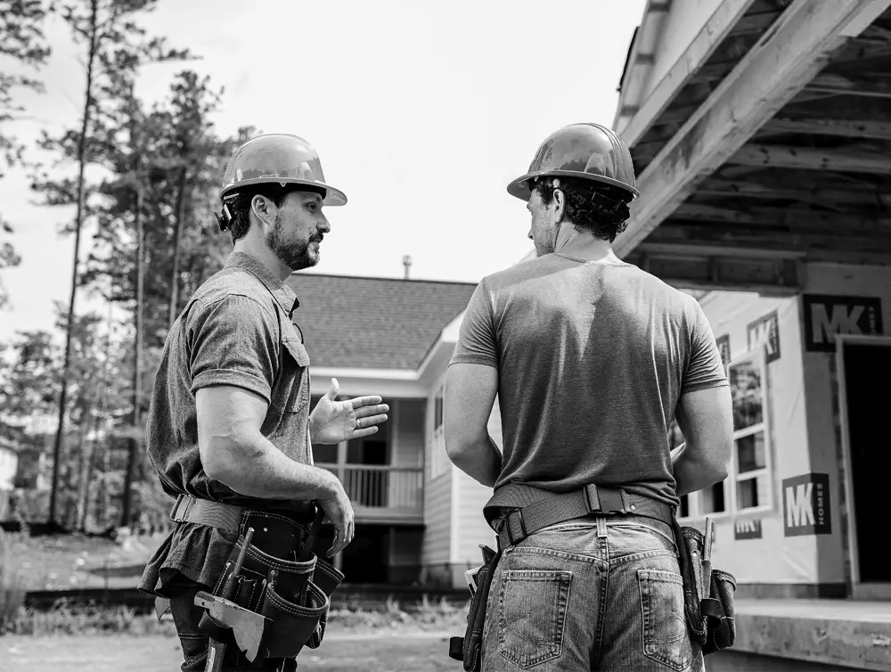 Two construction workers talking in driveway
